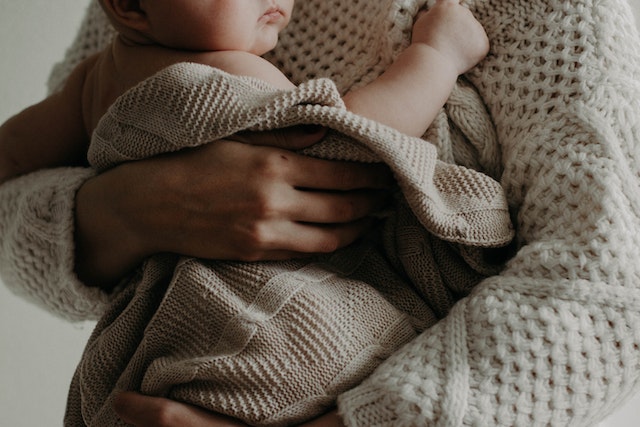 Baby carried in blanket by woman in sweater